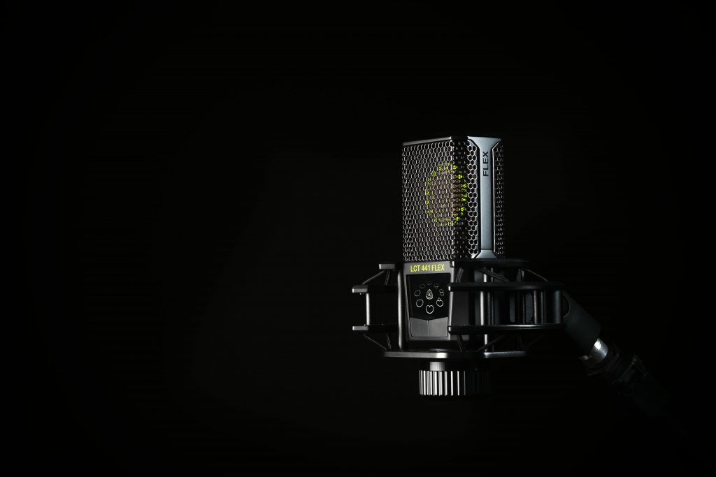 A detailed studio shot of a condenser microphone against a black background, emphasizing modern audio technology.