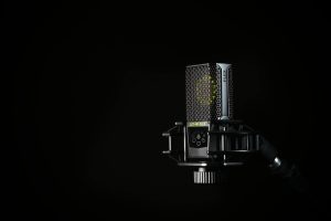 A detailed studio shot of a condenser microphone against a black background, emphasizing modern audio technology.